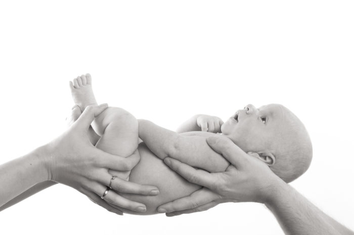 portfolio newborn jongetje close up ligt in handen van ouders
